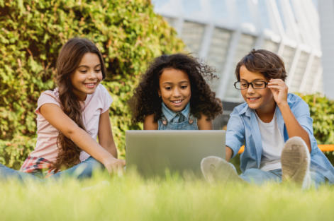 Diverse group of students doing school work on their laptop outdoors.